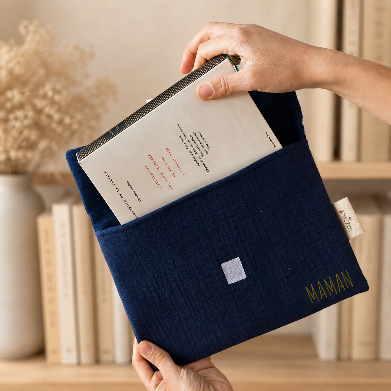pochette à livre bleu inscription "maman" pour la fête des mères devant bibiothèque beige